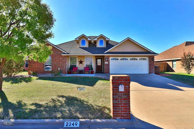 view of front of house featuring roof with shingles, concrete driveway, a front yard, an attached garage, and brick siding