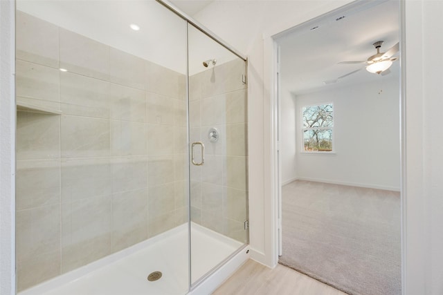 full bathroom featuring wood finished floors, a ceiling fan, a stall shower, and baseboards