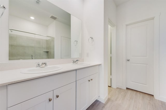 full bath featuring double vanity, wood finished floors, a shower stall, and a sink