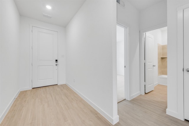 hall with visible vents, baseboards, and light wood-style floors