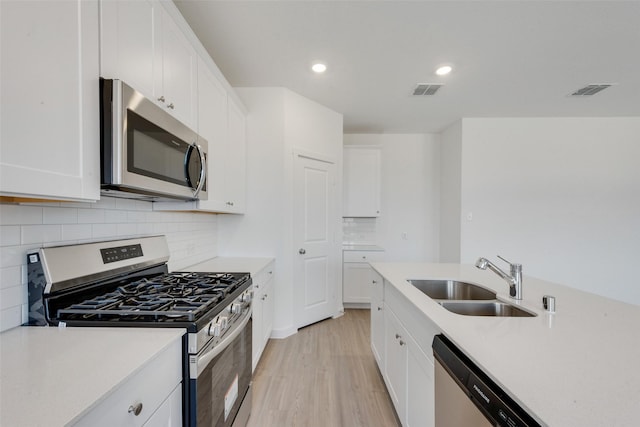 kitchen featuring light wood-style flooring, appliances with stainless steel finishes, light countertops, and a sink