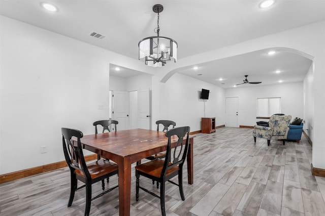 dining room featuring visible vents, arched walkways, light wood-style floors, and ceiling fan with notable chandelier