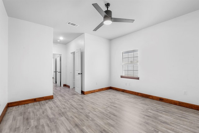 unfurnished room with ceiling fan, visible vents, light wood-type flooring, and baseboards