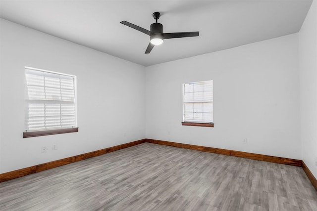 empty room featuring baseboards, wood finished floors, and a ceiling fan