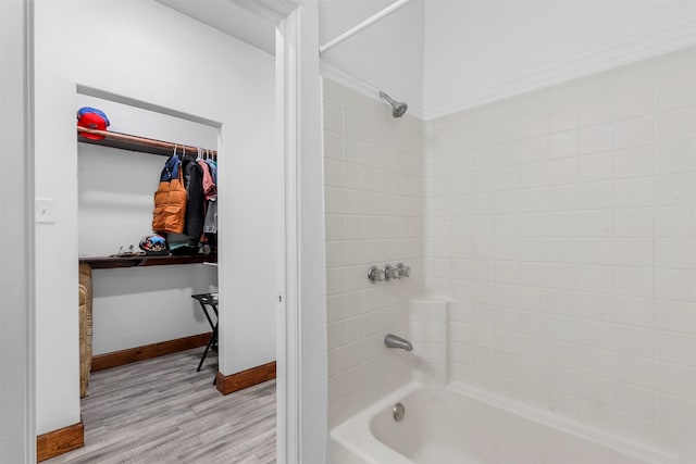 bathroom featuring a walk in closet,  shower combination, wood finished floors, and baseboards