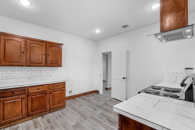 kitchen with light wood-style flooring, visible vents, backsplash, and light countertops