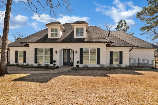 view of front of home with a front lawn, fence, french doors, and brick siding