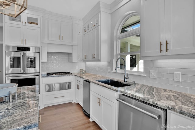 kitchen with white cabinetry, stainless steel appliances, a warming drawer, and a sink