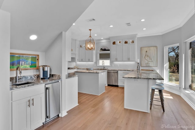 kitchen with visible vents, a sink, white cabinetry, dishwasher, and high end refrigerator