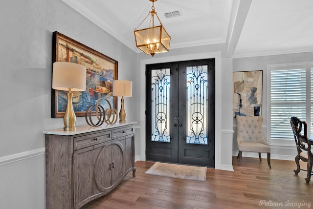 foyer with french doors, wood finished floors, and crown molding