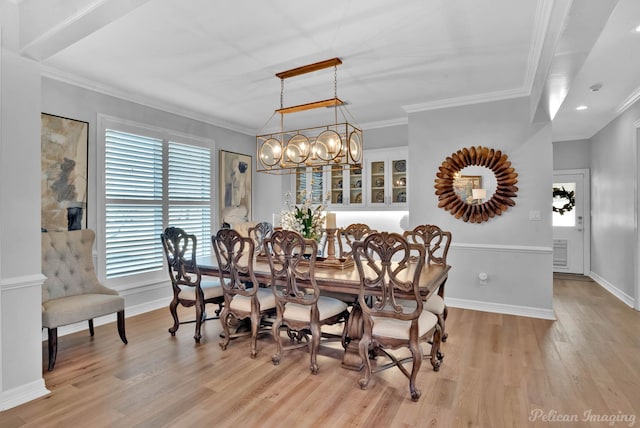 dining area featuring baseboards, light wood finished floors, and ornamental molding