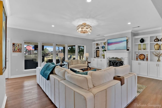 living area with a fireplace, wood finished floors, visible vents, and ornamental molding