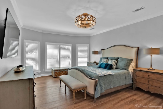 bedroom with visible vents, crown molding, baseboards, and wood finished floors