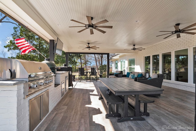 wooden deck featuring a ceiling fan, an outdoor kitchen, outdoor dining area, outdoor lounge area, and a grill