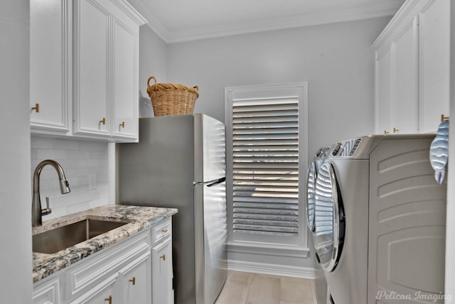 laundry area with washer and clothes dryer, ornamental molding, light wood-style floors, cabinet space, and a sink