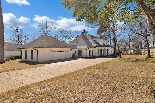 french country home featuring roof with shingles, concrete driveway, and a front lawn