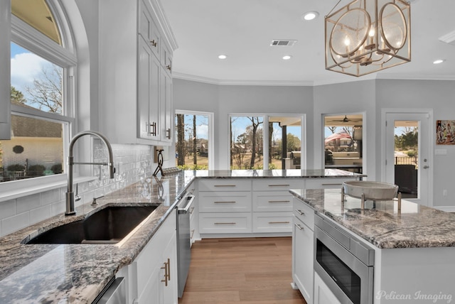 kitchen with ornamental molding, visible vents, appliances with stainless steel finishes, and a sink