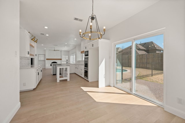 kitchen featuring light wood finished floors, open floor plan, recessed lighting, and white cabinetry