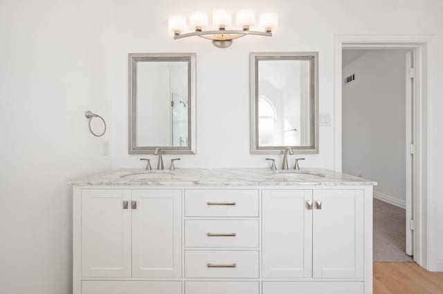 full bathroom with double vanity, visible vents, wood finished floors, and a sink