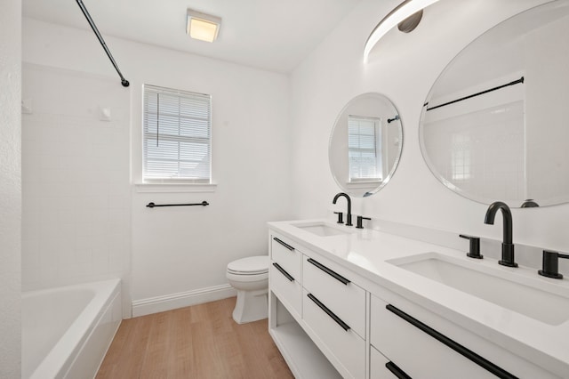 full bathroom featuring wood finished floors, toilet, baseboards, and a sink