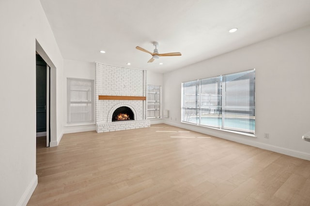 unfurnished living room with a fireplace, baseboards, light wood-type flooring, and ceiling fan