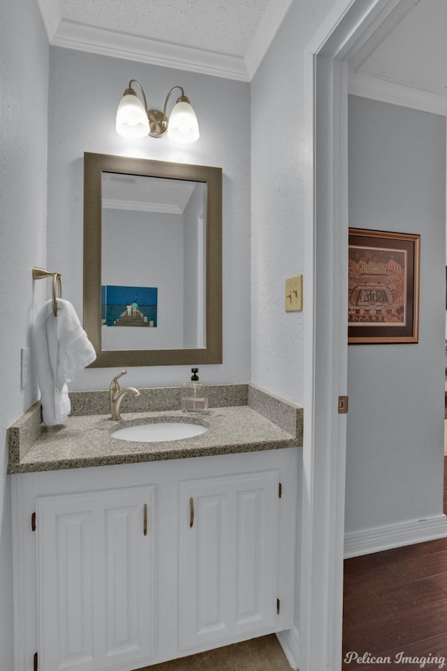 bathroom featuring vanity, wood finished floors, baseboards, and ornamental molding