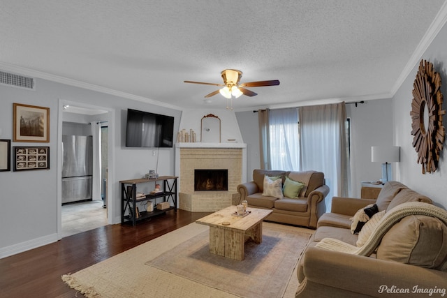 living room with ornamental molding, wood finished floors, visible vents, and a textured ceiling