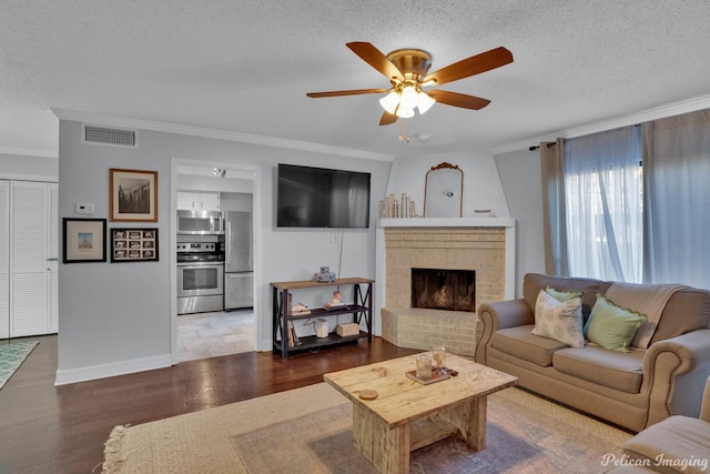 living room featuring visible vents, a textured ceiling, wood finished floors, and a fireplace