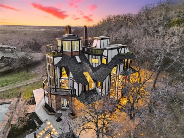 back of property at dusk with french doors and a chimney