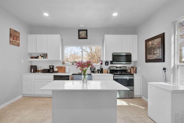 kitchen featuring decorative backsplash, appliances with stainless steel finishes, a center island, and light countertops