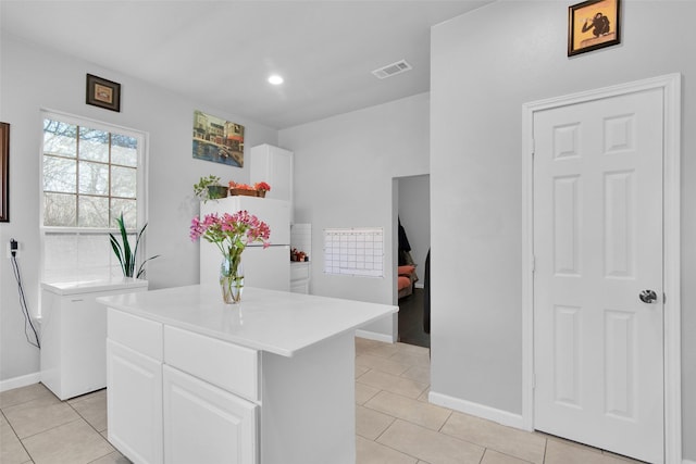 kitchen featuring visible vents, freestanding refrigerator, light tile patterned flooring, white cabinets, and light countertops