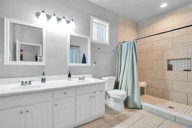 bathroom with a sink, tiled shower, toilet, and double vanity