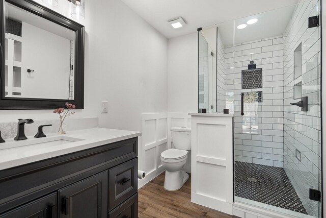 full bathroom featuring vanity, toilet, wood finished floors, and a stall shower