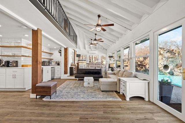 interior space featuring ceiling fan, beamed ceiling, light wood finished floors, and high vaulted ceiling