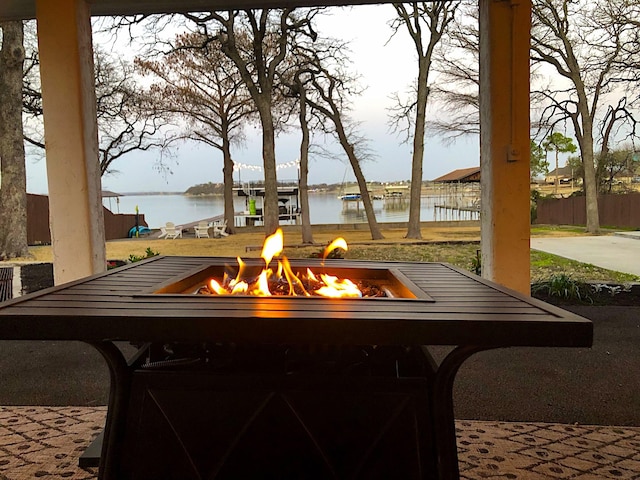 view of patio / terrace with an outdoor fire pit, fence, and a water view