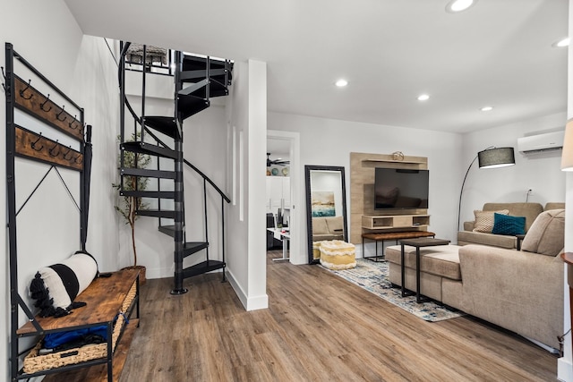 living area featuring an AC wall unit, wood finished floors, recessed lighting, stairway, and baseboards