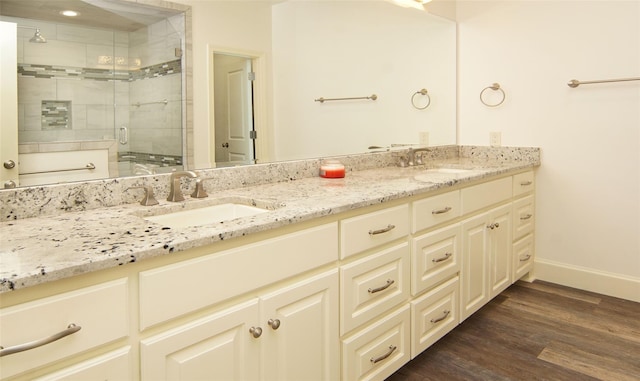 full bathroom featuring a sink, a shower stall, wood finished floors, and double vanity