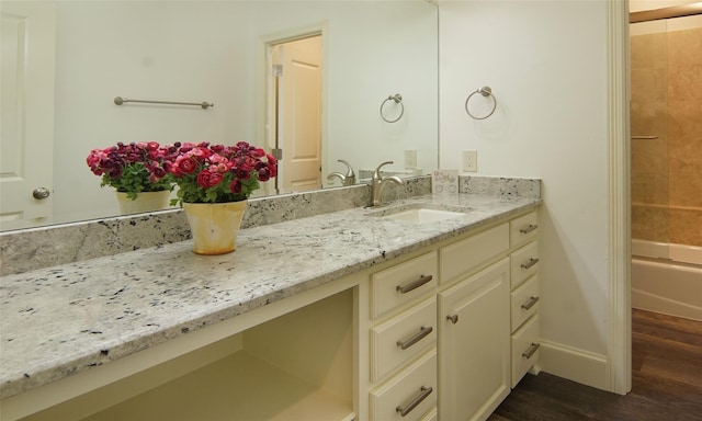 bathroom with baseboards, bathtub / shower combination, wood finished floors, and vanity