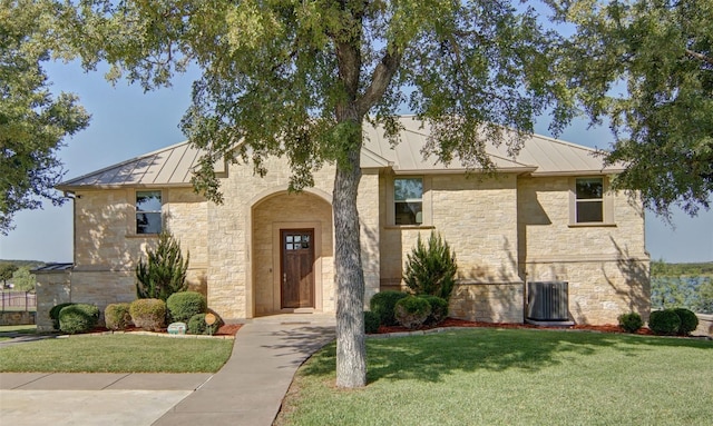 view of front of home featuring a standing seam roof, a front lawn, stone siding, and metal roof