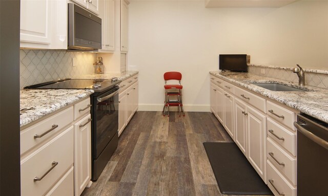 kitchen with dark wood-type flooring, a sink, stainless steel dishwasher, black range with electric cooktop, and decorative backsplash