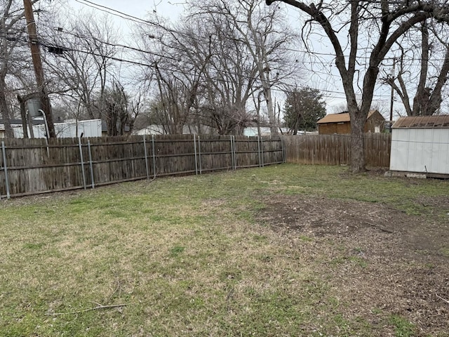 view of yard with a fenced backyard, an outdoor structure, and a shed