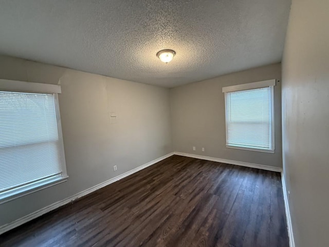 empty room with dark wood-style floors, baseboards, and a textured ceiling