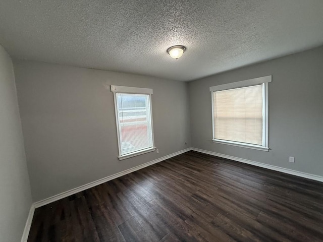 spare room featuring baseboards, a textured ceiling, and dark wood-style flooring