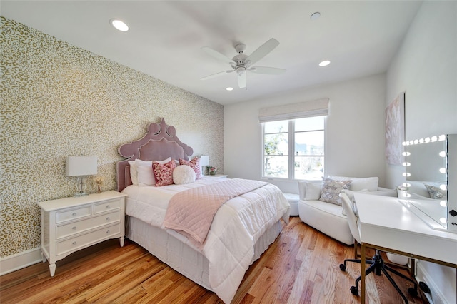 bedroom featuring light wood finished floors, wallpapered walls, an accent wall, recessed lighting, and a ceiling fan