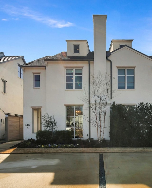 view of front of house featuring stucco siding and a chimney