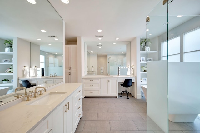 full bath with visible vents, a freestanding tub, and a sink