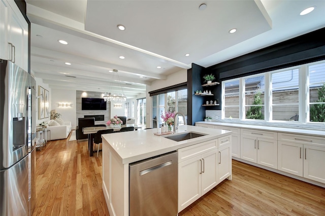 kitchen with open floor plan, beamed ceiling, light countertops, stainless steel appliances, and a sink