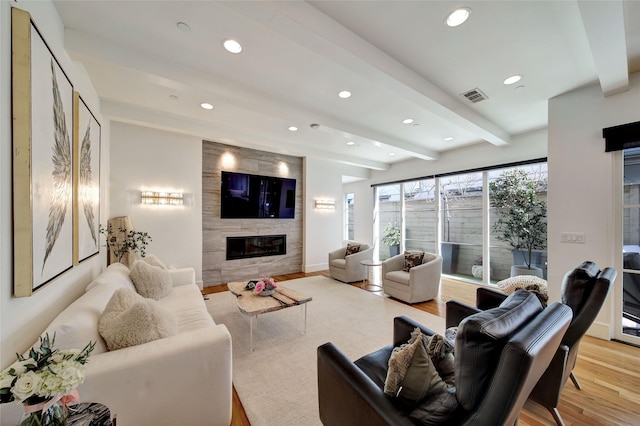 living area featuring light wood finished floors, visible vents, beamed ceiling, recessed lighting, and a fireplace