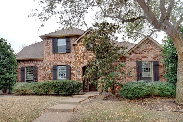 view of front of property featuring stone siding, brick siding, and roof with shingles