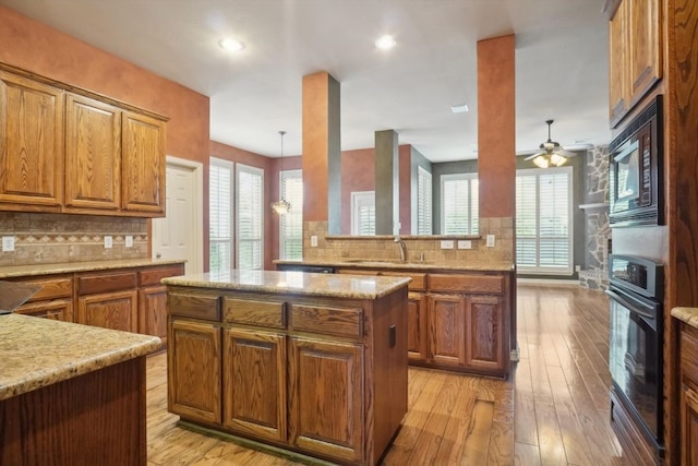 kitchen featuring a sink, brown cabinets, black appliances, and a glass covered fireplace